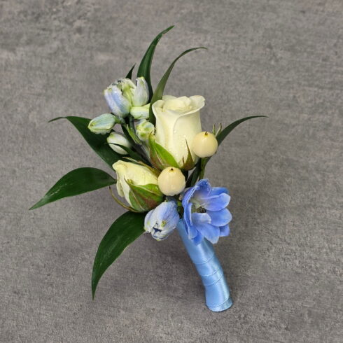 Blue and white deluxe boutonniere with white roses and blue delphinium by BLOOMSI florist in Oakville and Mississauga